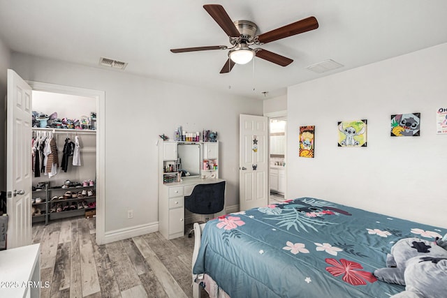 bedroom featuring light hardwood / wood-style flooring, stainless steel refrigerator, ceiling fan, a walk in closet, and a closet