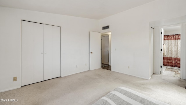 unfurnished bedroom featuring ensuite bathroom, light carpet, and a closet