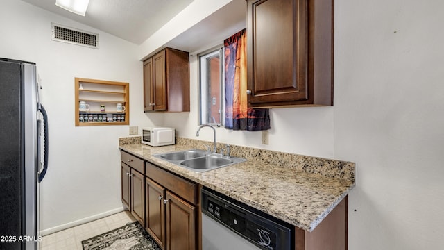 kitchen with light stone countertops, vaulted ceiling, appliances with stainless steel finishes, and sink