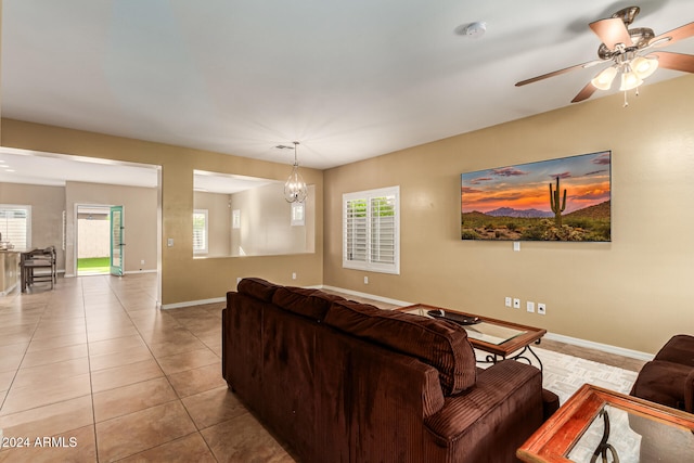 tiled living room featuring ceiling fan with notable chandelier