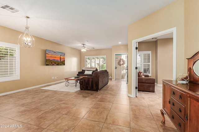 living room featuring light tile patterned flooring and ceiling fan with notable chandelier