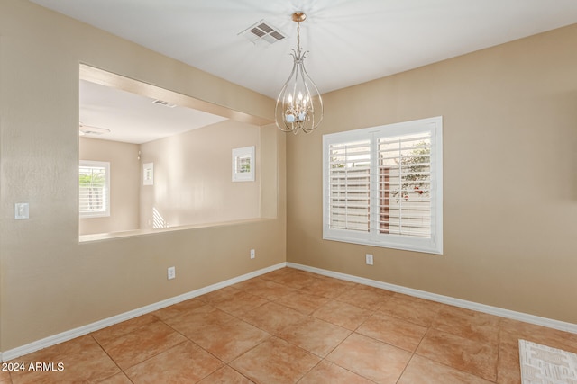 empty room featuring an inviting chandelier and light tile patterned floors