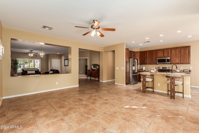 kitchen featuring stainless steel appliances, a breakfast bar area, sink, ceiling fan, and pendant lighting