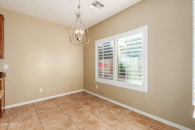 unfurnished dining area with light tile patterned floors, a healthy amount of sunlight, and a notable chandelier