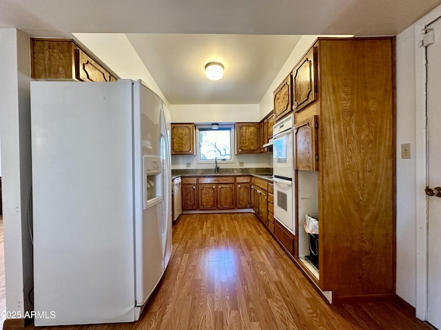 kitchen featuring sink, white appliances, and light hardwood / wood-style flooring