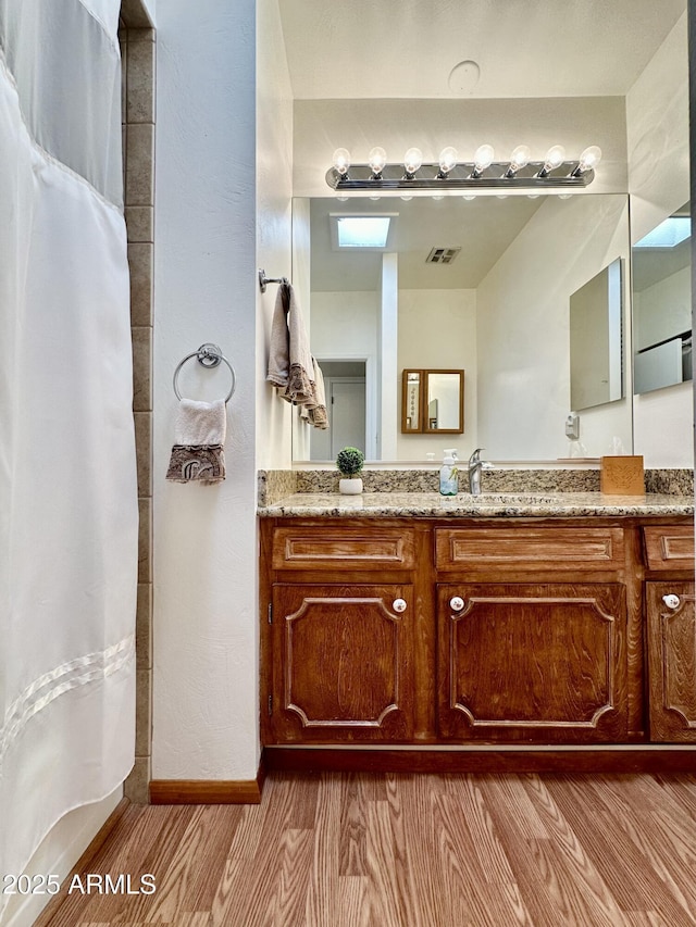 bathroom featuring hardwood / wood-style flooring, vanity, and curtained shower