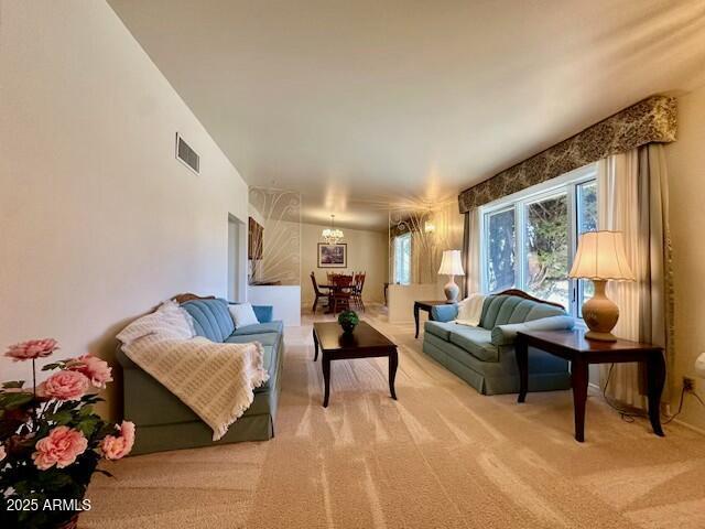 living room with carpet and an inviting chandelier