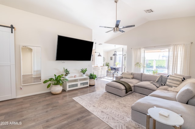 living room featuring ceiling fan, hardwood / wood-style flooring, lofted ceiling, and a barn door