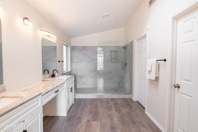 bathroom featuring hardwood / wood-style floors, tiled shower, lofted ceiling, and vanity