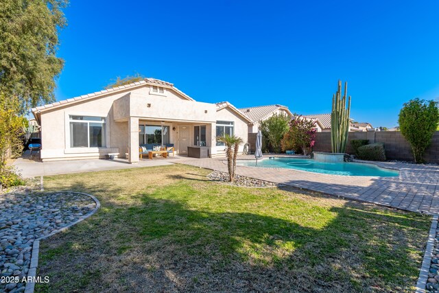 rear view of house with a fenced in pool, a lawn, and a patio