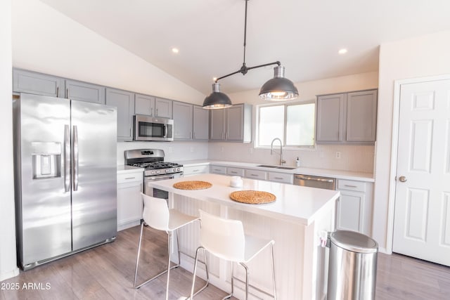 kitchen with appliances with stainless steel finishes, sink, decorative light fixtures, tasteful backsplash, and a kitchen island