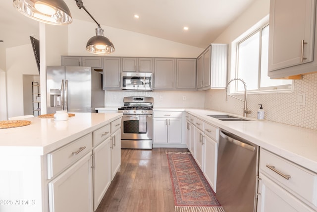 kitchen featuring pendant lighting, sink, dark wood-type flooring, lofted ceiling, and stainless steel appliances