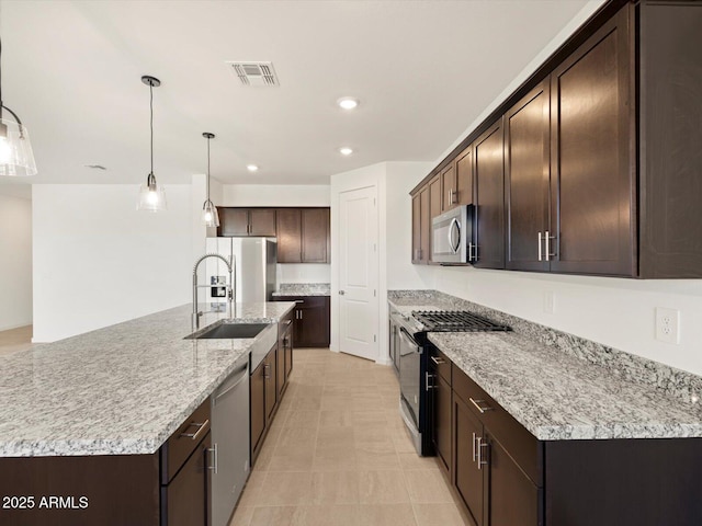 kitchen featuring pendant lighting, an island with sink, appliances with stainless steel finishes, dark brown cabinets, and sink