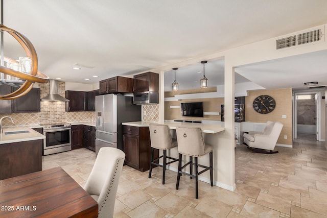2256 S Las Flores, Mesa, AZ 85202 - kitchen with wall chimney exhaust hood, appliances with stainless steel finishes, dark brown cabinets, a sink, and light countertops