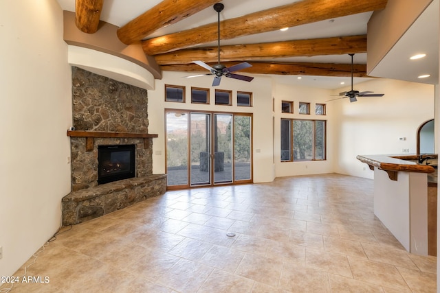 unfurnished living room featuring beamed ceiling, ceiling fan, and a fireplace