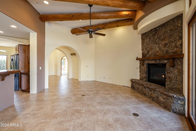 unfurnished living room featuring beamed ceiling, ceiling fan, a fireplace, and light tile patterned floors