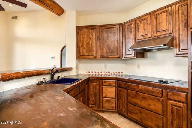 kitchen featuring beam ceiling, black electric stovetop, light tile patterned floors, and sink