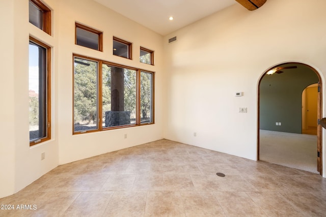 spare room featuring a towering ceiling and light tile patterned floors