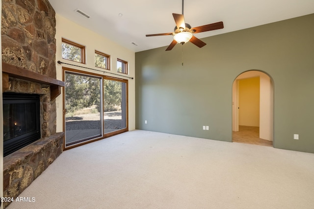 unfurnished living room with a fireplace, light colored carpet, and ceiling fan