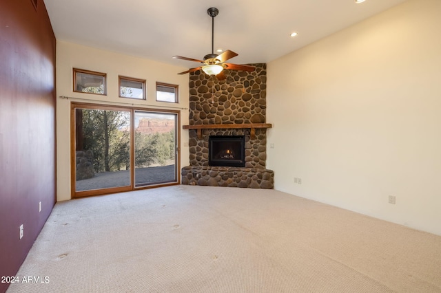 unfurnished living room featuring a high ceiling, ceiling fan, light colored carpet, and a fireplace