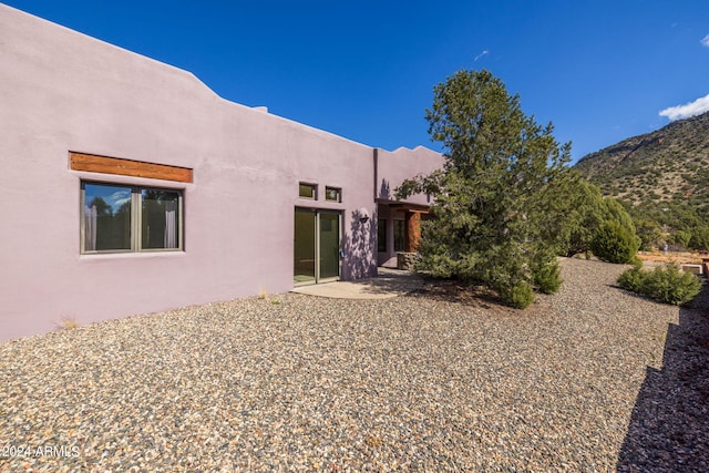 back of property featuring a mountain view and a patio area