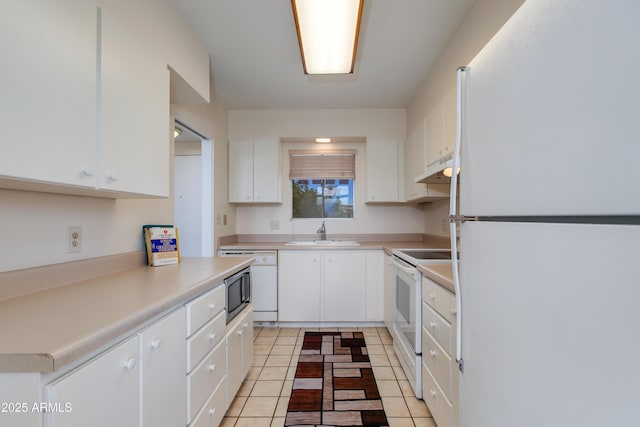 kitchen featuring white appliances, under cabinet range hood, light countertops, a sink, and white cabinetry