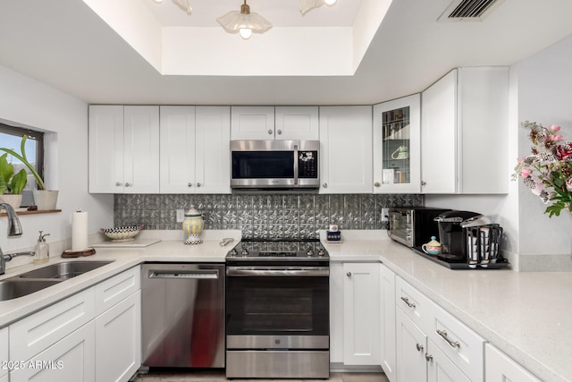 1401 E Puget Ave Unit 4, Phoenix, AZ 85020 - kitchen with appliances with stainless steel finishes, a sink, a tray ceiling, white cabinetry, and light countertops