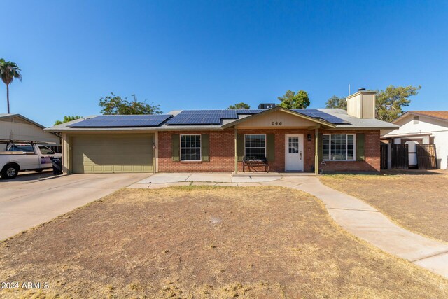 single story home featuring solar panels and a garage