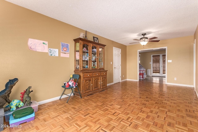 spare room with a ceiling fan, a textured ceiling, and baseboards