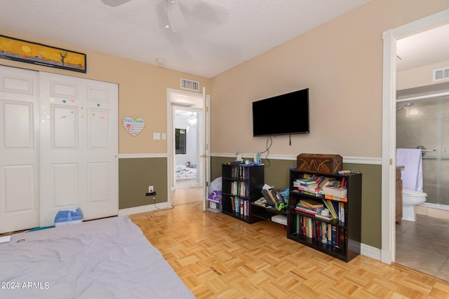 bedroom featuring a textured ceiling, light parquet floors, ceiling fan, and ensuite bathroom