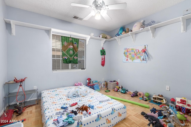 bedroom featuring a ceiling fan, baseboards, visible vents, and a textured ceiling