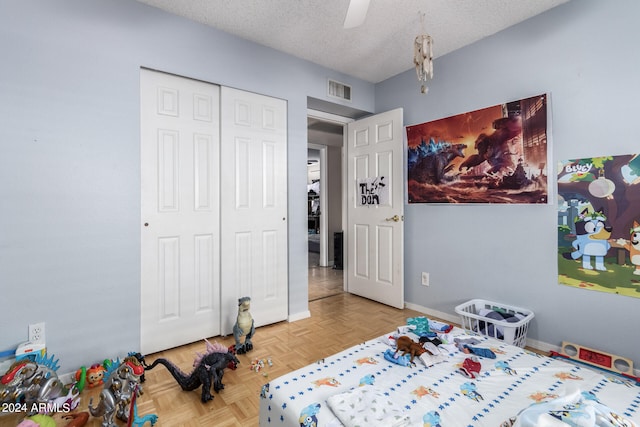 bedroom with a textured ceiling, ceiling fan, a closet, and light parquet flooring