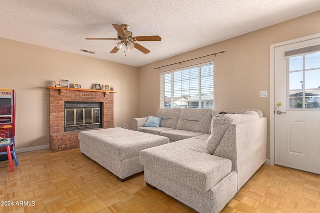 living area featuring a wealth of natural light, a brick fireplace, visible vents, and a textured ceiling