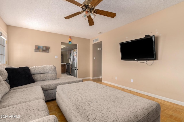 living area featuring a textured ceiling, a ceiling fan, visible vents, and baseboards