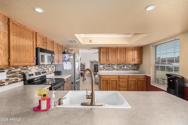 kitchen with a tray ceiling, visible vents, stainless steel appliances, and a sink