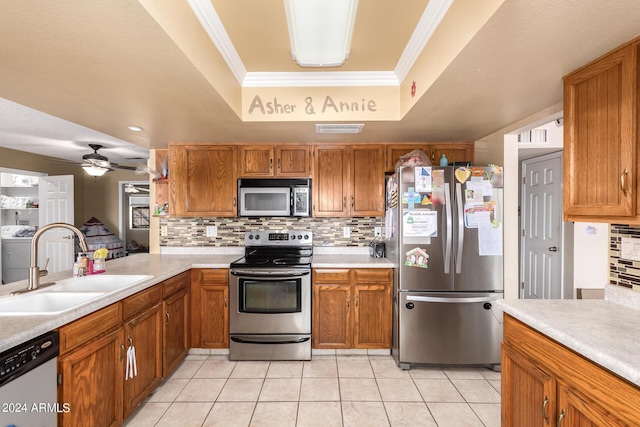 kitchen with stainless steel appliances, a sink, ornamental molding, independent washer and dryer, and a tray ceiling