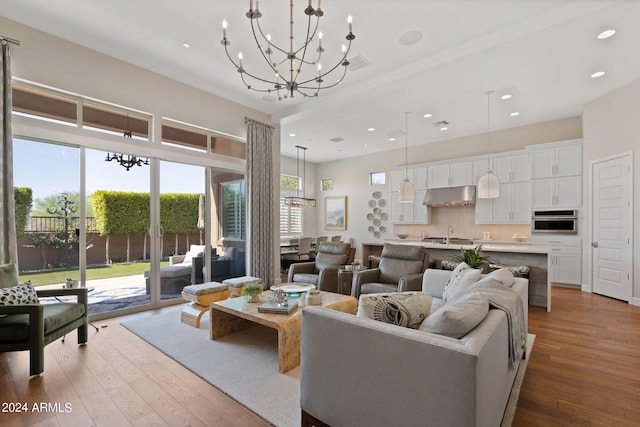 living room with wood-type flooring, an inviting chandelier, and sink