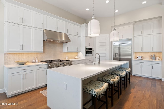 kitchen featuring white cabinetry, dark wood-type flooring, an island with sink, backsplash, and high end appliances