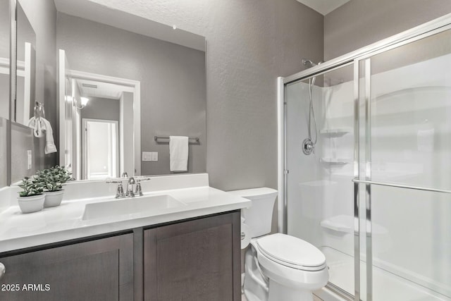 bathroom with a shower with door, vanity, and toilet