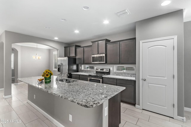 kitchen featuring dark brown cabinetry, stainless steel appliances, sink, and an island with sink