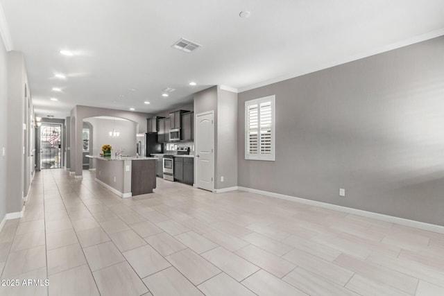 kitchen featuring a kitchen bar, sink, ornamental molding, appliances with stainless steel finishes, and a kitchen island with sink