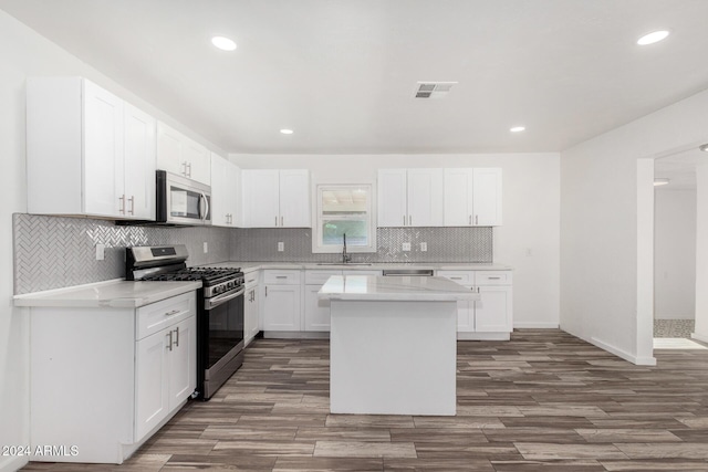 kitchen featuring a center island, sink, appliances with stainless steel finishes, white cabinetry, and wood-type flooring