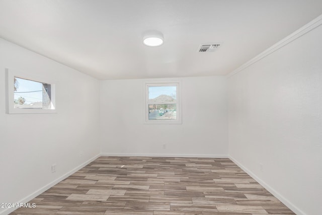 unfurnished room with light hardwood / wood-style floors, crown molding, and a healthy amount of sunlight