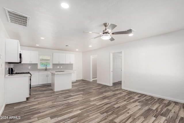 kitchen featuring a kitchen island, ceiling fan, hardwood / wood-style flooring, white stove, and white cabinetry