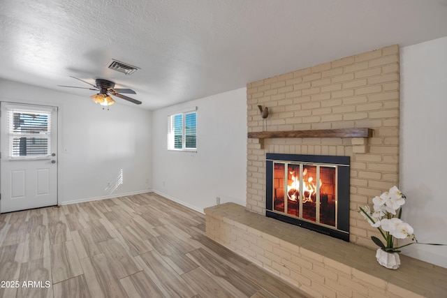 unfurnished living room featuring a healthy amount of sunlight, a textured ceiling, a fireplace, and light hardwood / wood-style flooring