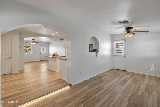 unfurnished room with ceiling fan, a wealth of natural light, a textured ceiling, and light wood-type flooring