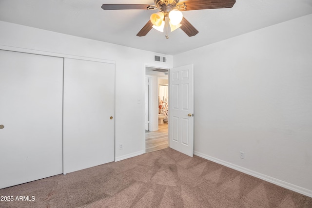 unfurnished bedroom featuring light colored carpet, a closet, and ceiling fan