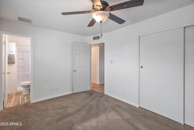 unfurnished bedroom featuring ceiling fan, ensuite bath, carpet floors, and a closet