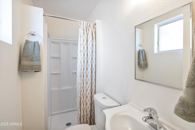 bathroom featuring sink, a shower with curtain, and toilet