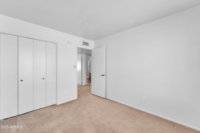 unfurnished bedroom with light colored carpet and a closet